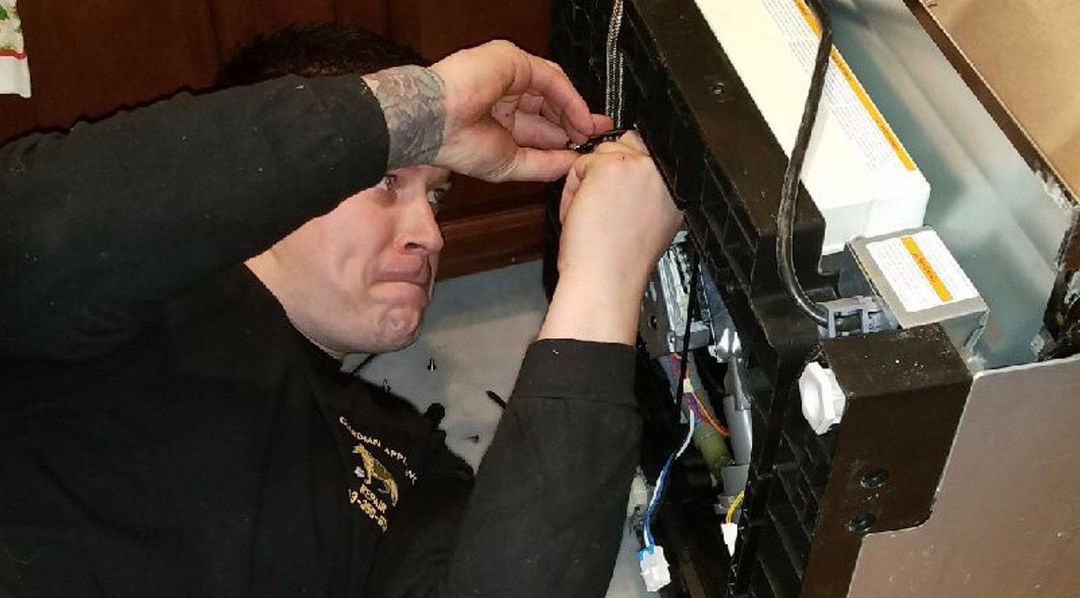 On-site repair in a Littleton-area kitchen — technician in a Guardian Appliance Repair shirt working inside an open appliance.